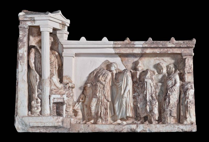 Ανάγλυφο σε μορφή ναΐσκου και στοάς, που βρέθηκε στο ιερό του Ασκληπιού στην Ακρόπολη. Παριστάνονται ο Ασκληπιός, η σύζυγός του Ηπιόνη και η κόρη τους Υγεία ενώ υποδέχονται ομάδα λατρευτών, περίπου 350 π.Χ. Μουσείο Ακρόπολης