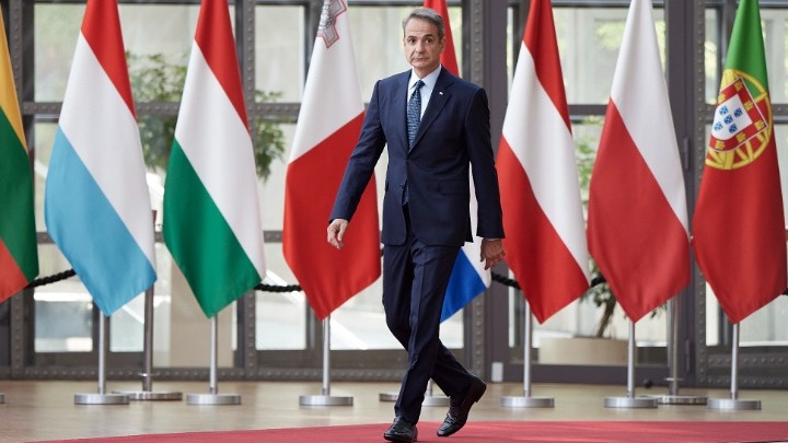 Ο Κυριάκος Μητσοτάκης περπατά μπροστά από σημαίες των κρατών της ΕΕ